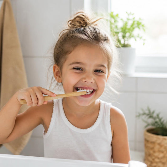 Smiling child brushing teeth with a bamboo toothbrush