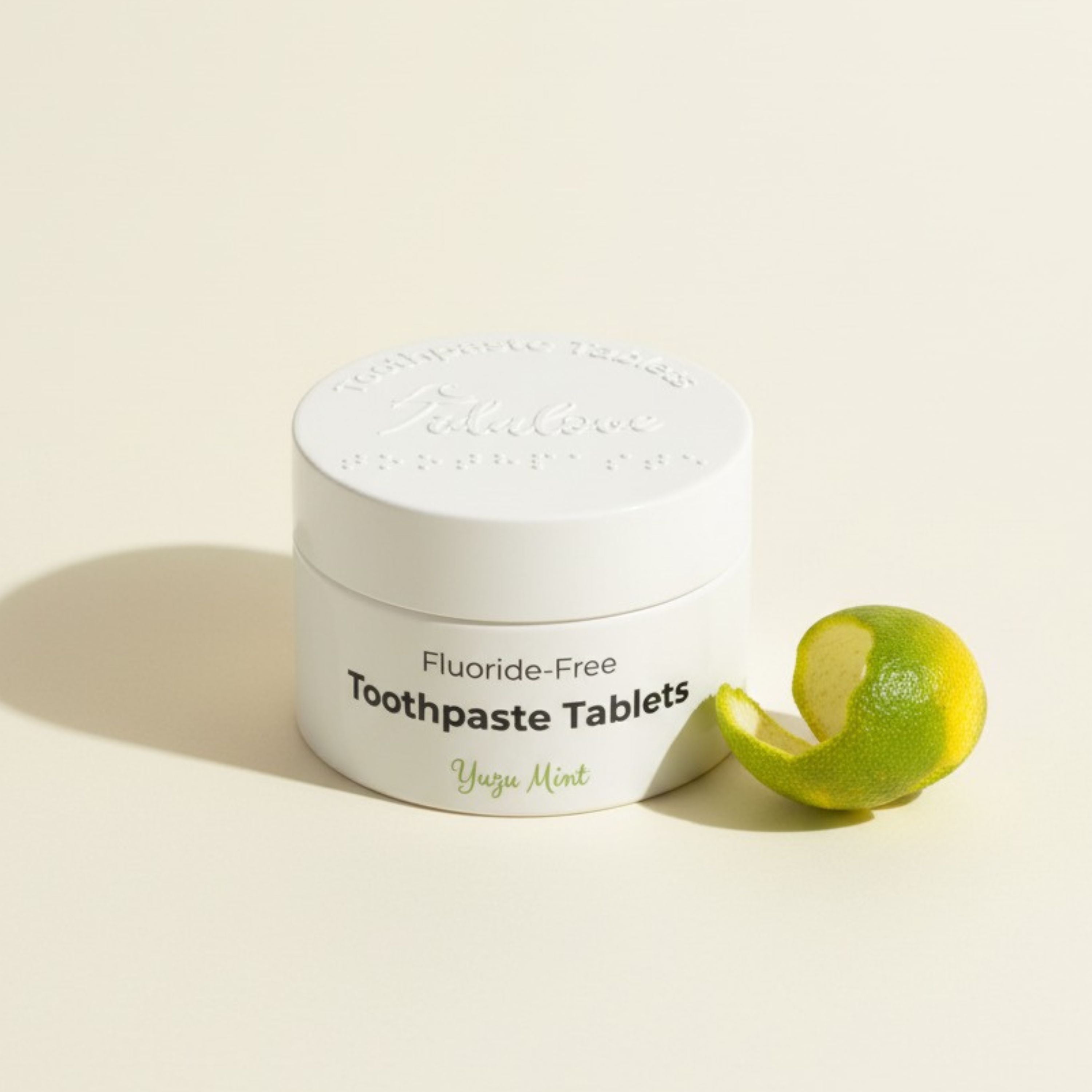 Jar of fluoride-free toothpaste tablets with a lime on a light background