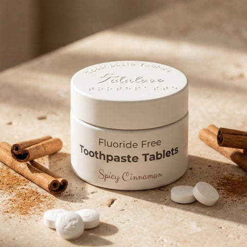 Jar of fluoride-free toothpaste tablets with cinnamon sticks and tablets on a wooden surface