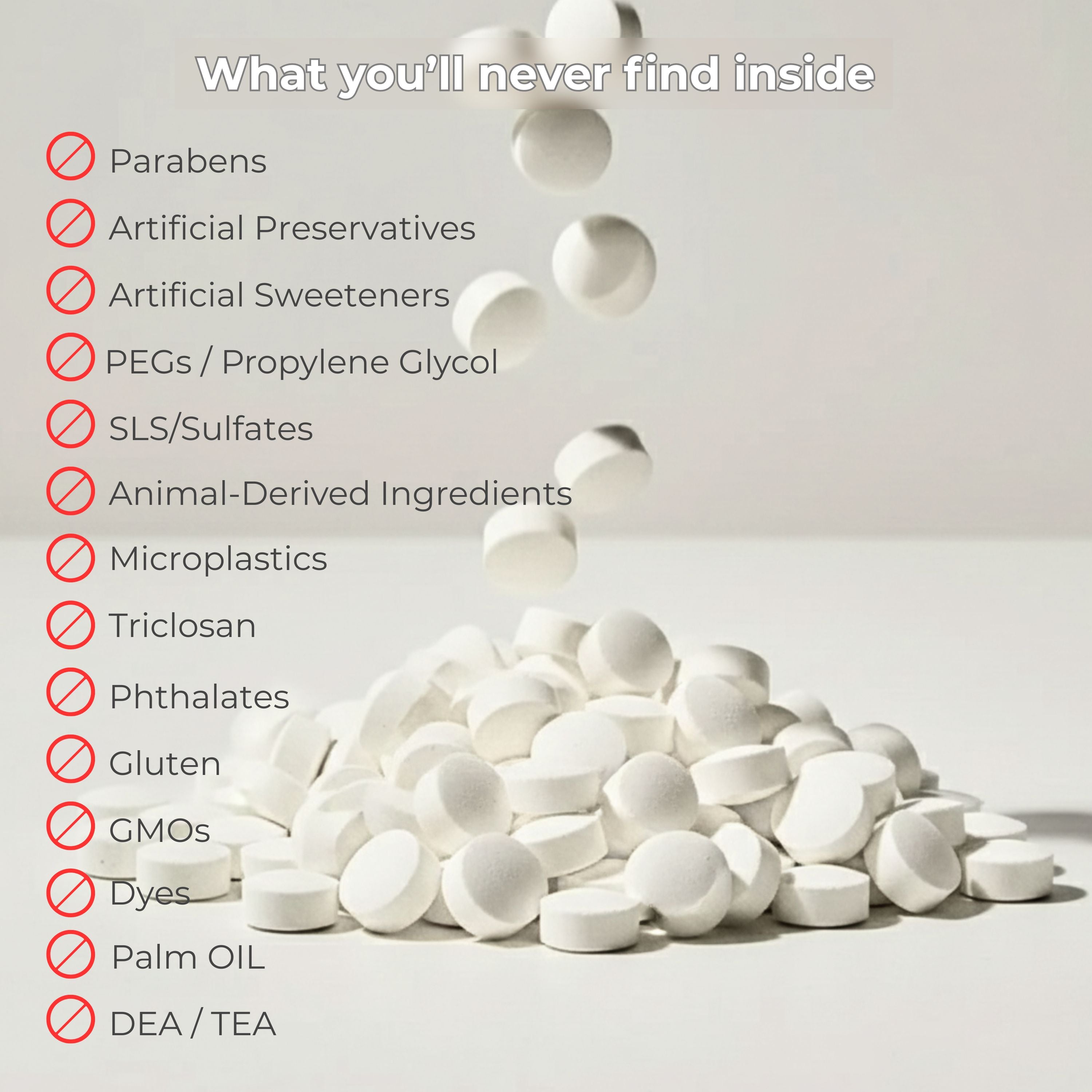 White toothpaste tablets with a list of ingredients not found inside on a light gray background

