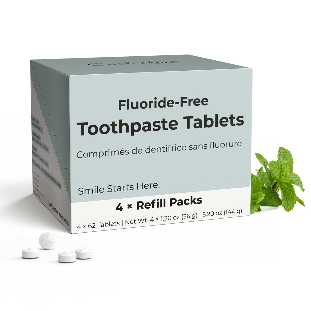 Fluoride-free toothpaste tablets with packaging and mint leaves on a white background