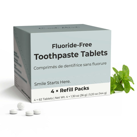 Fluoride-free toothpaste tablets with packaging and mint leaves on a white background