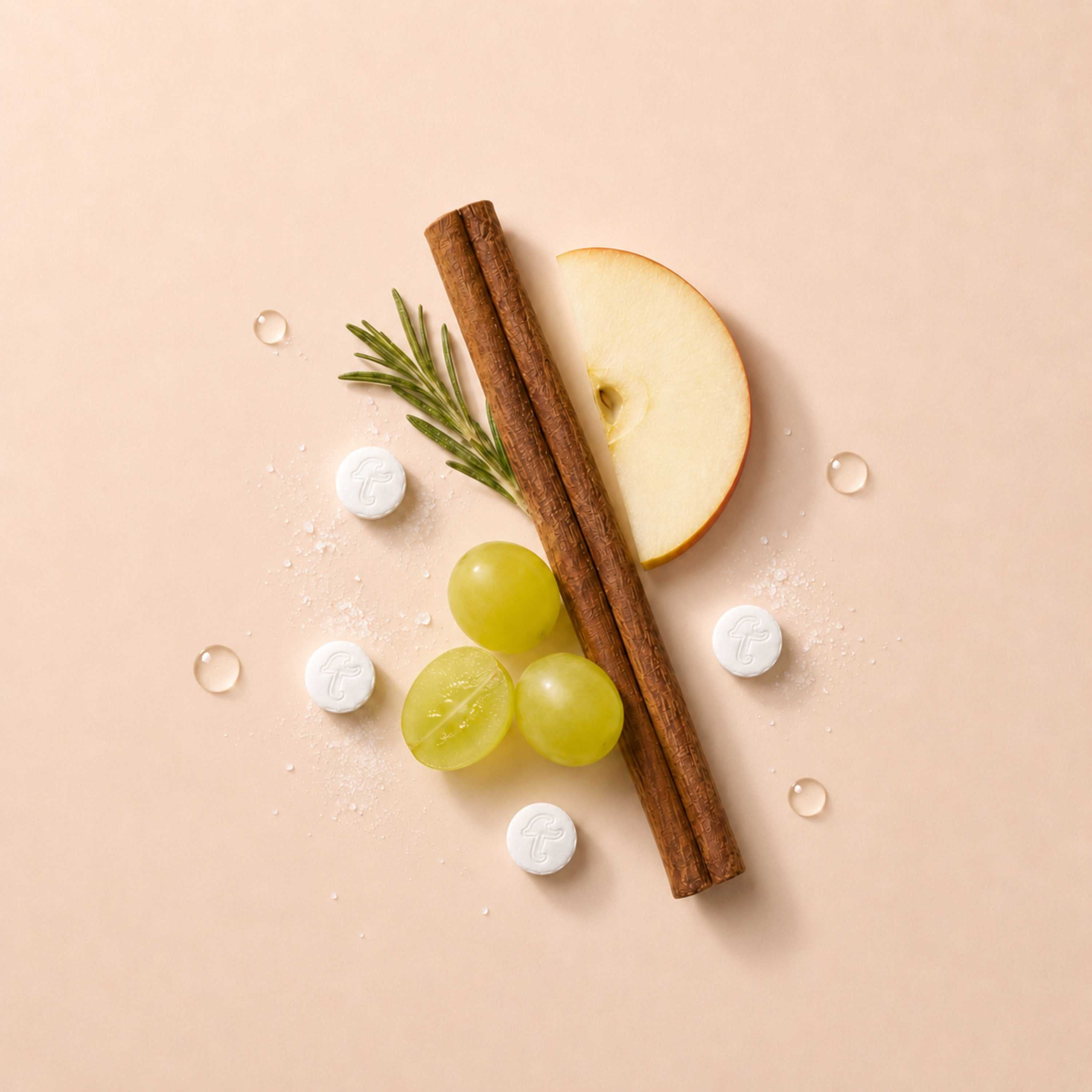 Tidalove Spicy Cinnamon toothpaste tablets styled with cinnamon sticks, 
sliced apple, and green grapes on a blush pink background